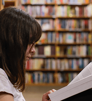 Woman reading book in library.